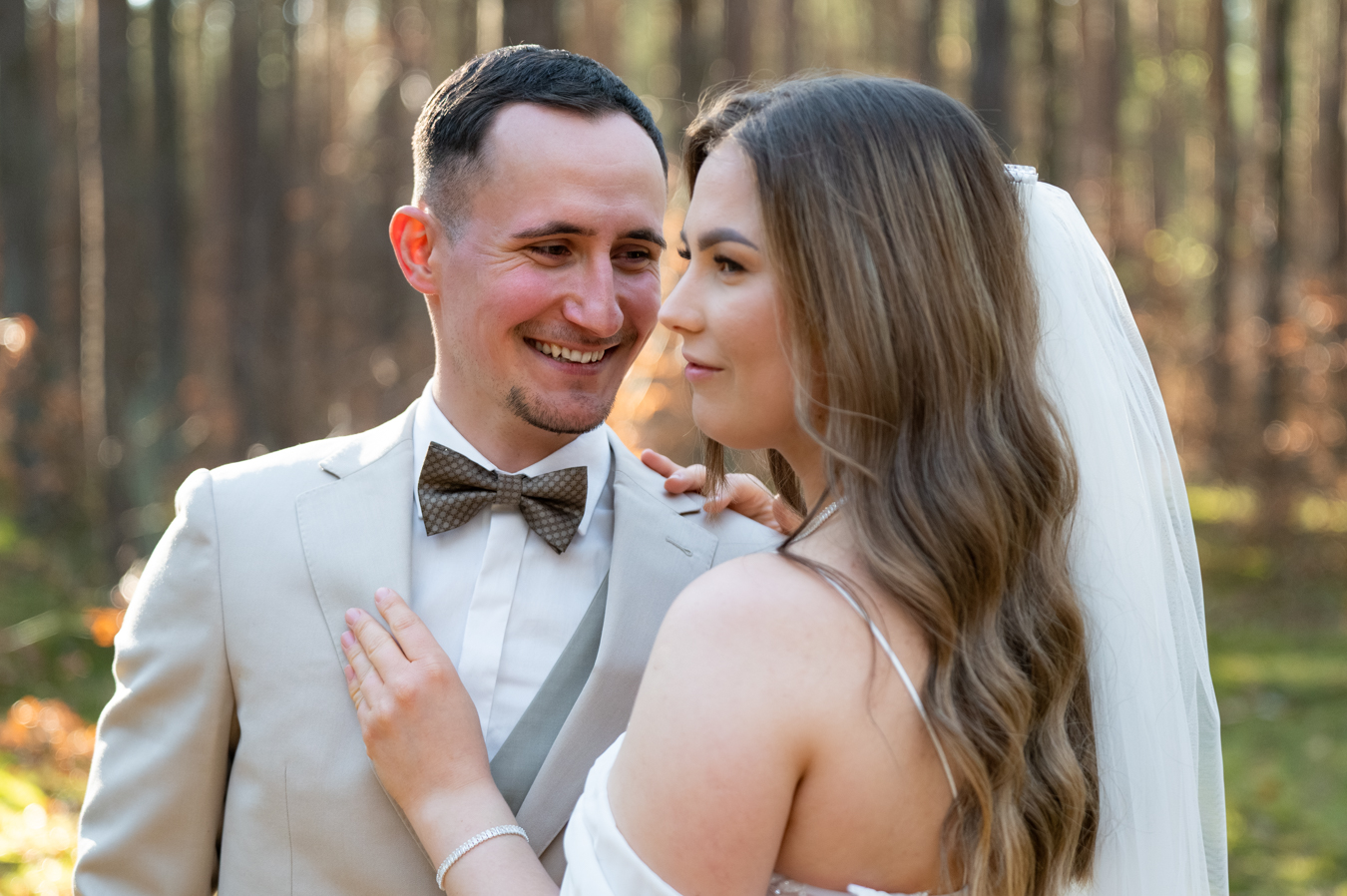 Pan młody zapina marynarkę podczas przygotowań do ślubu, świadek podaje poszetkę