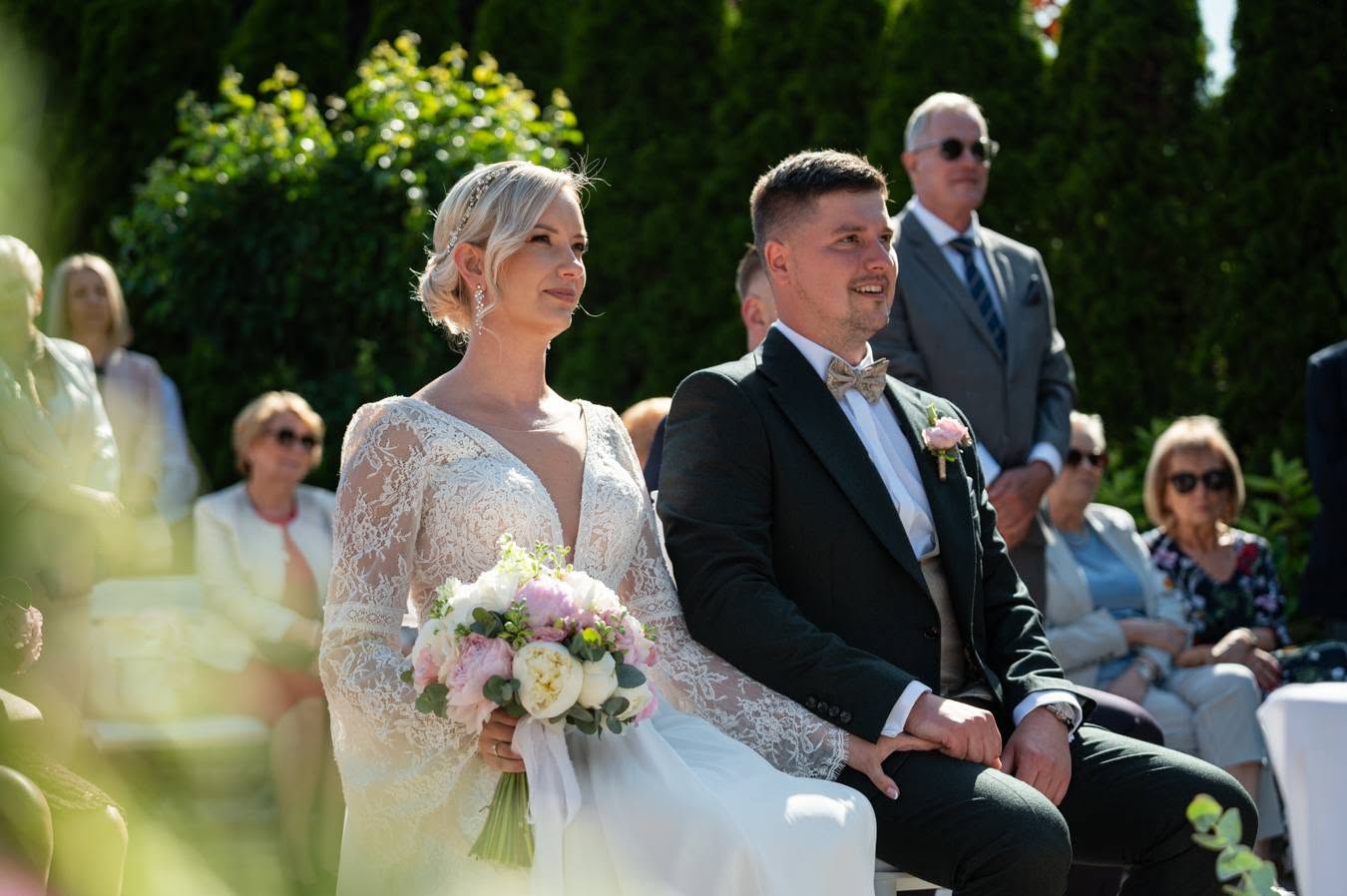 Ceremonia ślubna w plenerze, para młoda i goście w tle