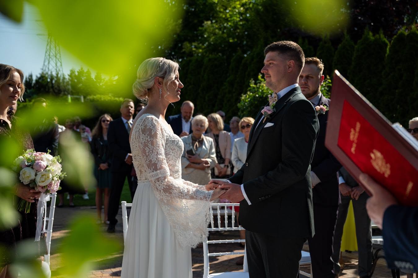 Para młoda trzymająca się za ręce podczas ceremonii w plenerze