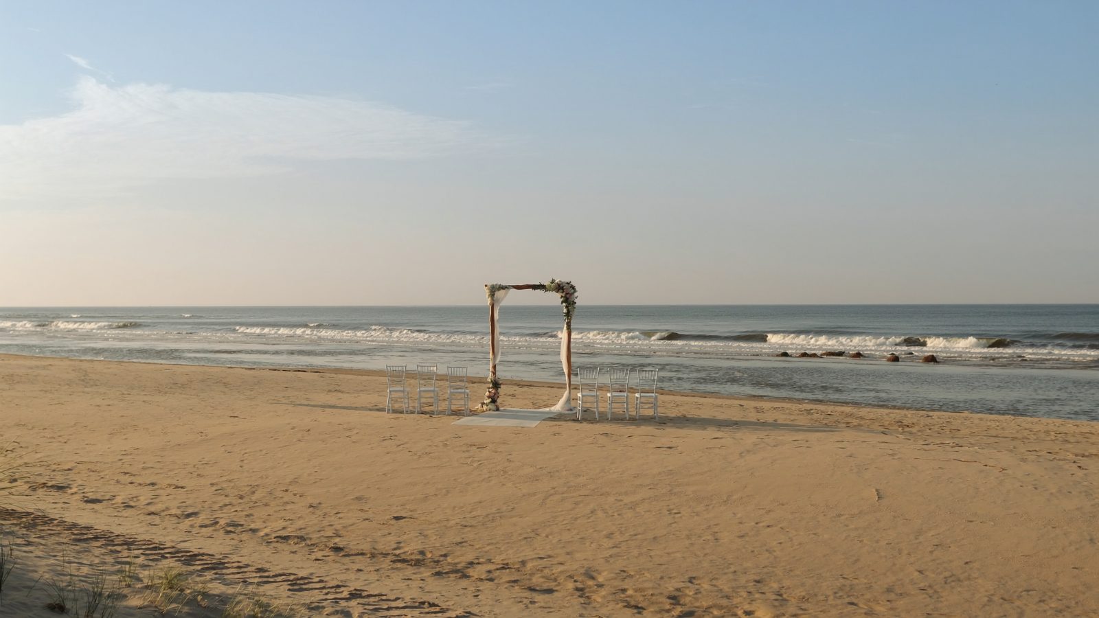 Wesele nad morzem, drewniany ołtarz i krzesła na plaży o zachodzie słońca